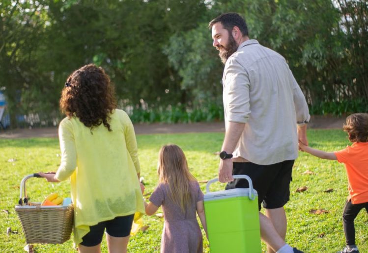 A family of four enjoys a picnic in a sunny park, capturing a joyful day outdoors.