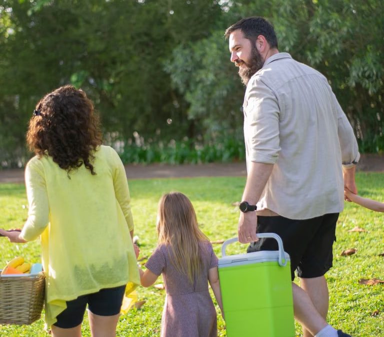 A family of four enjoys a picnic in a sunny park, capturing a joyful day outdoors.